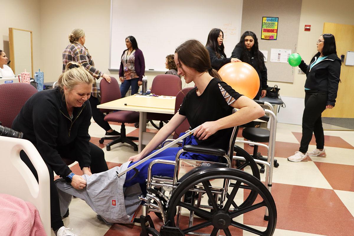 Two San Juan College students utilizing equipment for training in a wheelchair and using stretch bands.